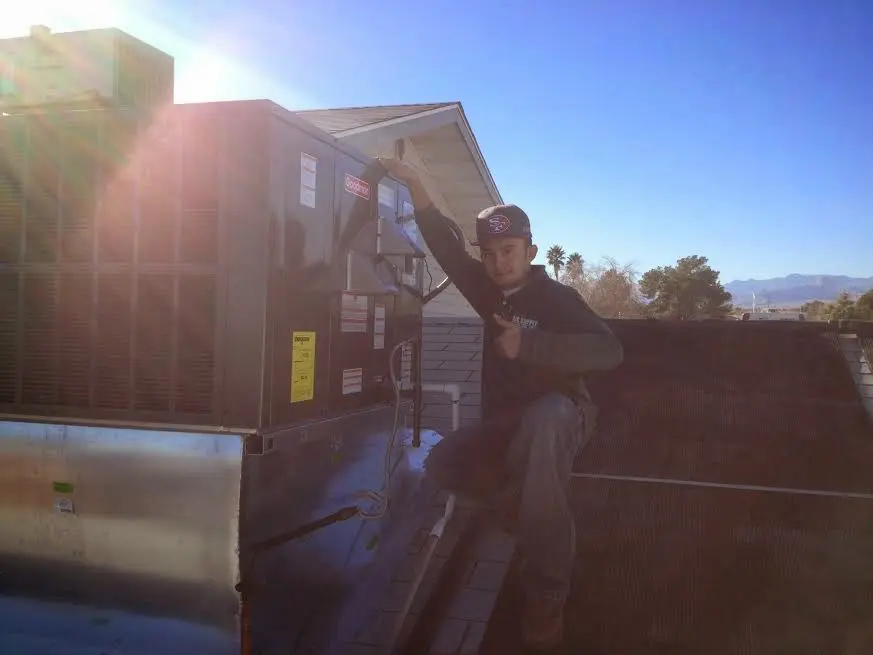HVAC technician performing Heat Pump Repair on a rooftop unit in Doney Park